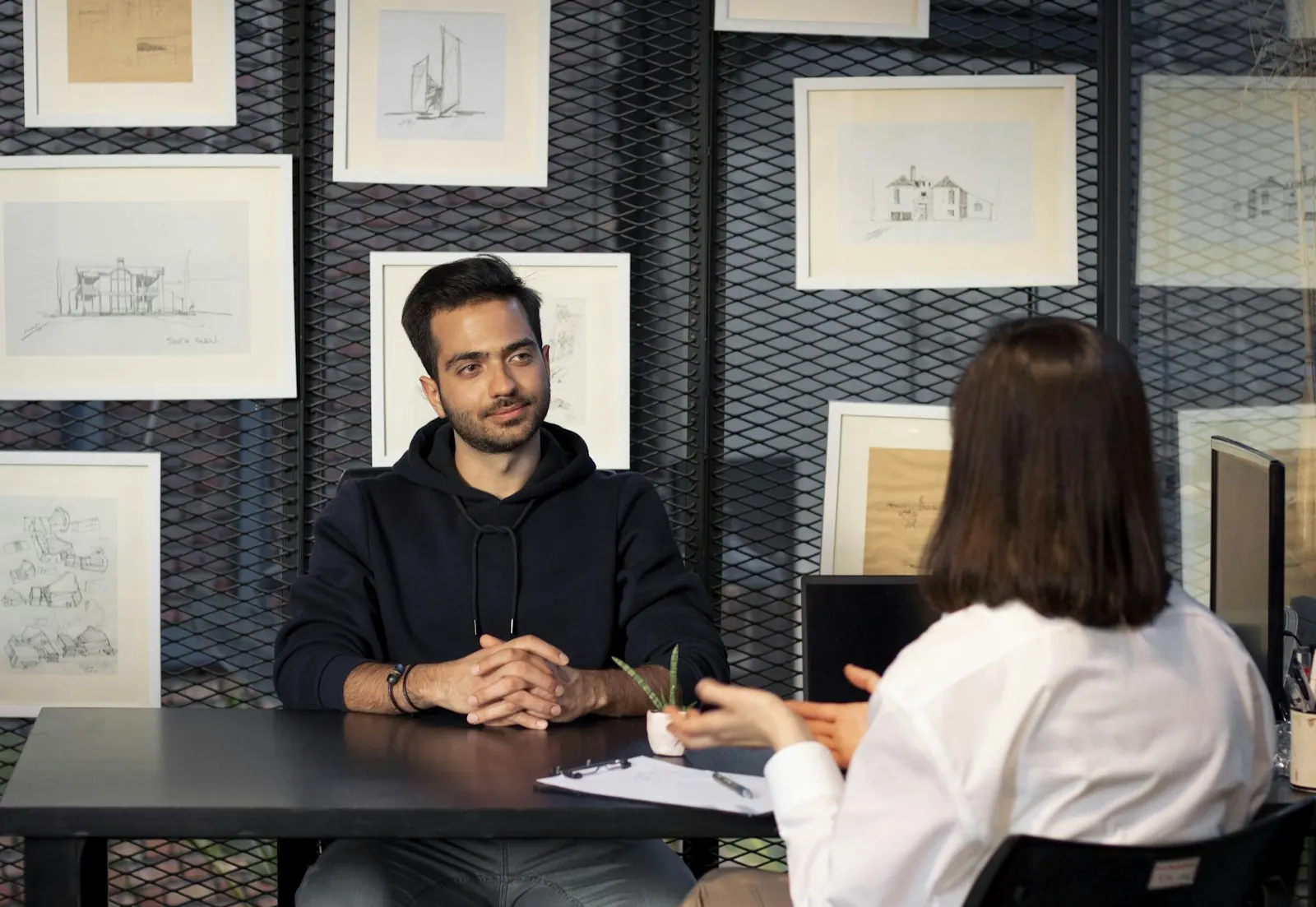 Duas pessoas conversando sentadas a uma mesa, numa entrevista